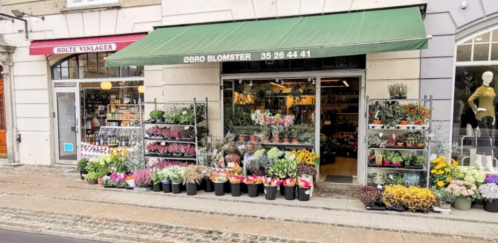Streetview af Øbro Blomster på Østerbrogade — det grønne markisetag med navn og telefonnummer 35 26 44 41, plus blomsterstanden foran butikken
